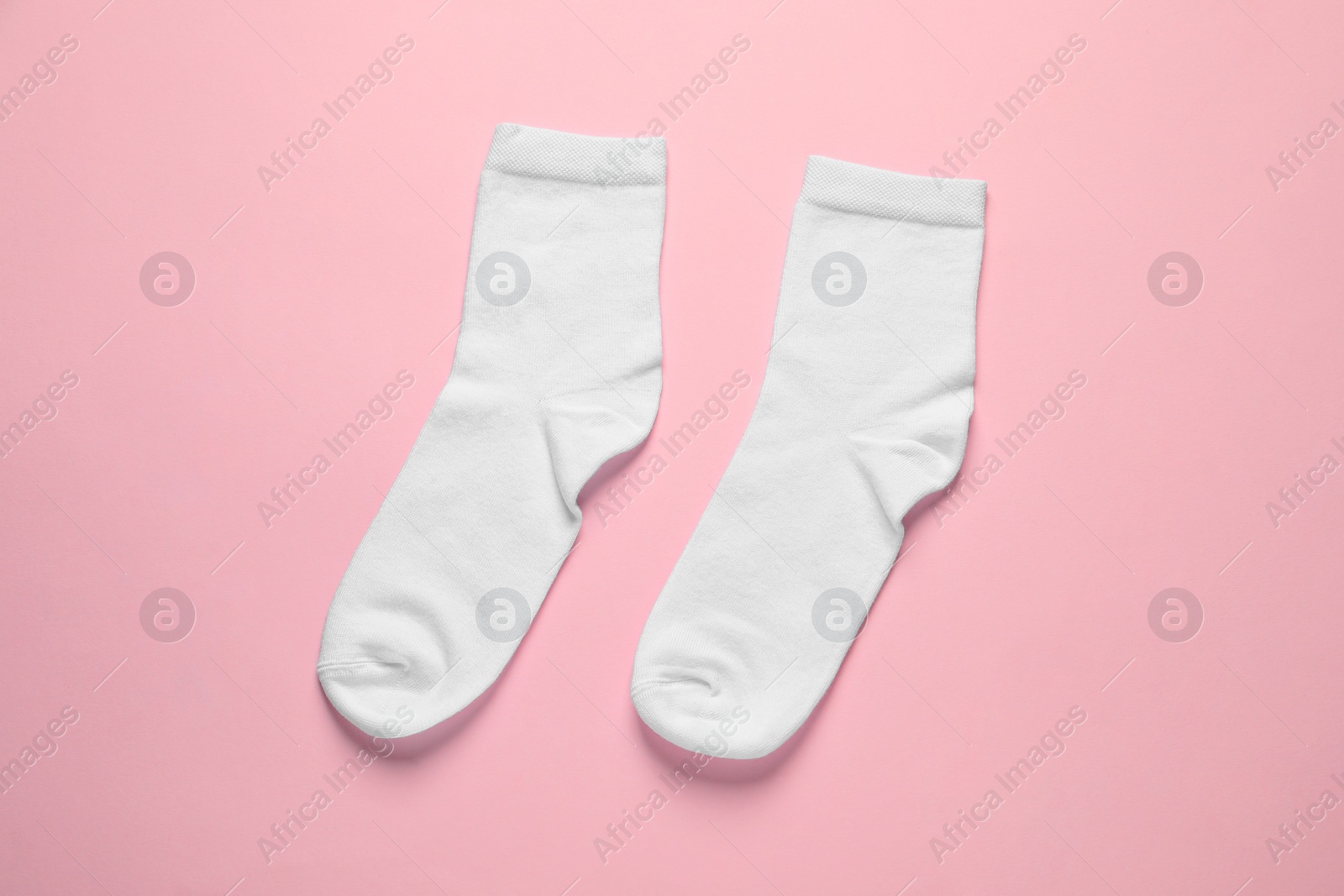 Photo of Pair of white socks on pink background, flat lay