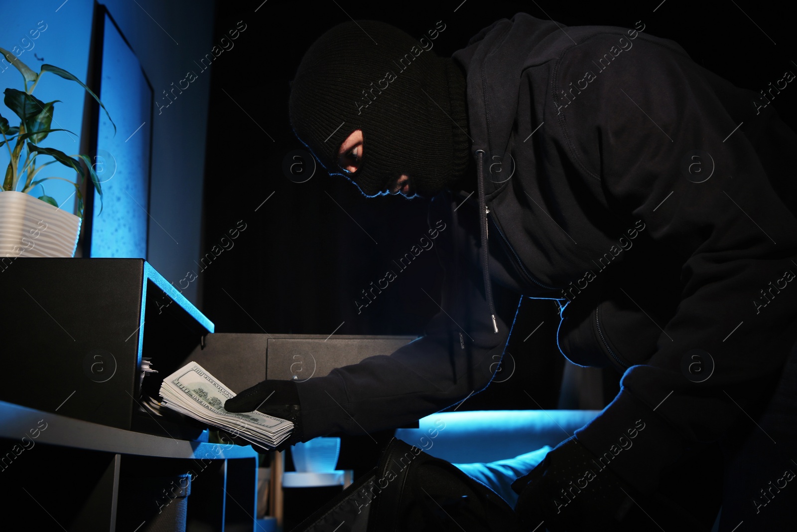 Photo of Thief taking money out of steel safe indoors at night