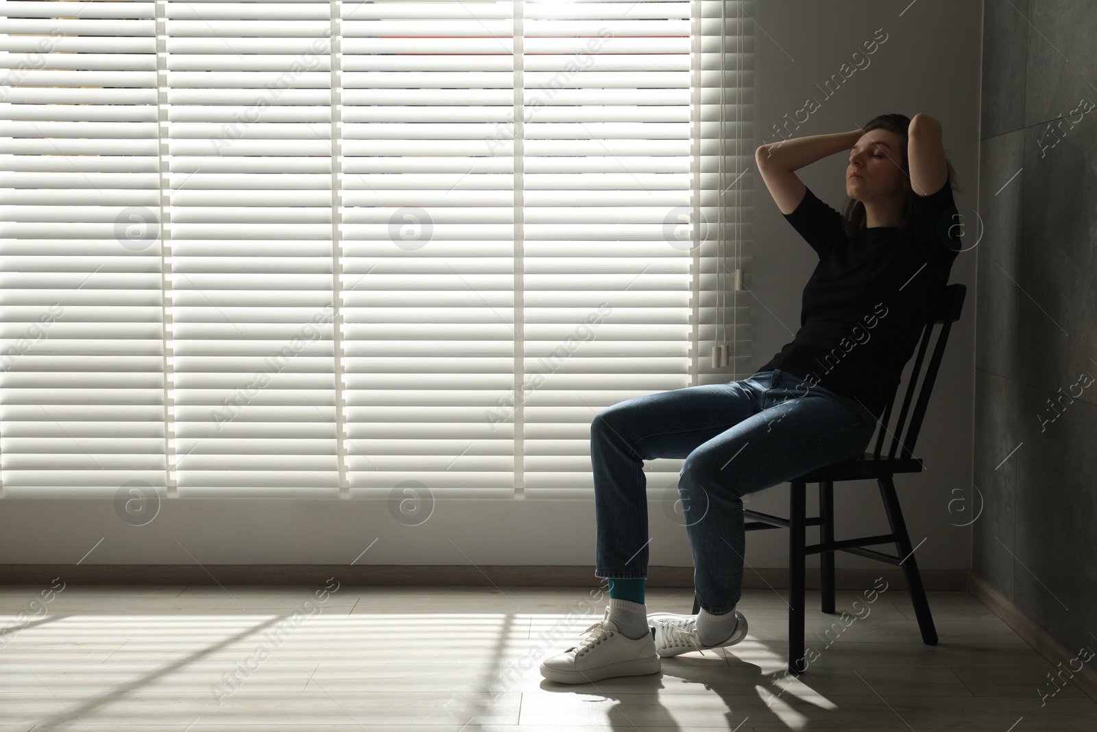 Photo of Sad young woman sitting on chair at home, space for text