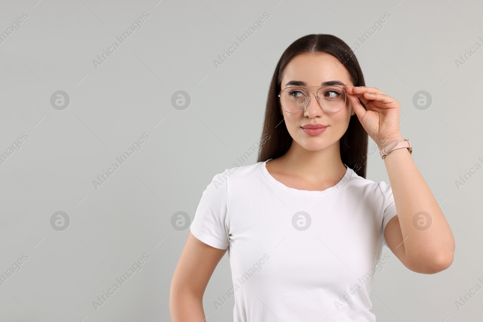 Photo of Beautiful woman wearing glasses on light gray background, space for text