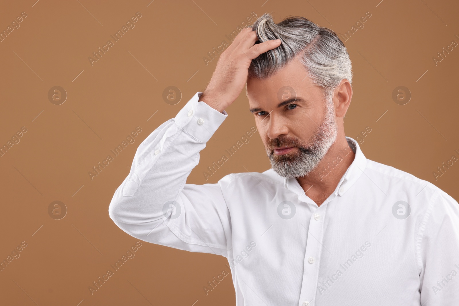 Photo of Portrait of confident man with beautiful hairstyle on light brown background