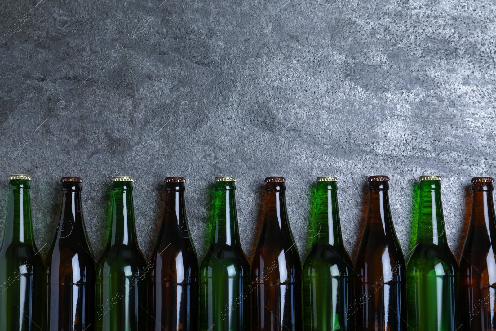 Photo of Bottles with beer on grey table, flat lay. Space for text