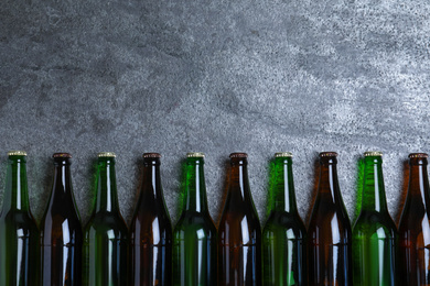 Bottles with beer on grey table, flat lay. Space for text