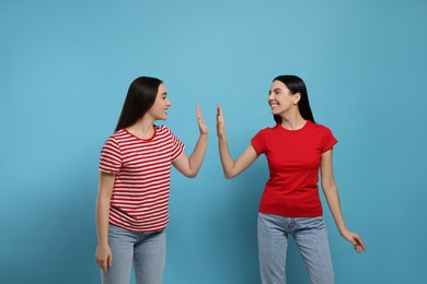 Women giving high five on light blue background