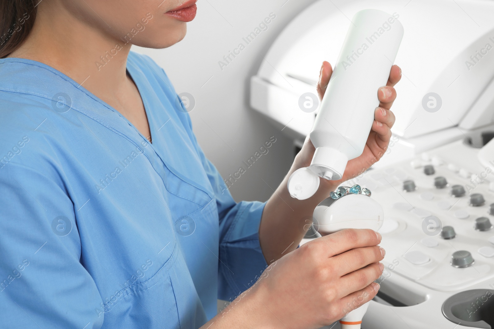 Photo of Sonographer covering ultrasound machine probe with gel in clinic, closeup