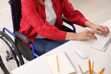 Photo of Woman in wheelchair typing on keyboard indoors, closeup