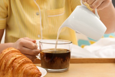 Photo of Woman pouring milk into cup with hot drink in bed, closeup