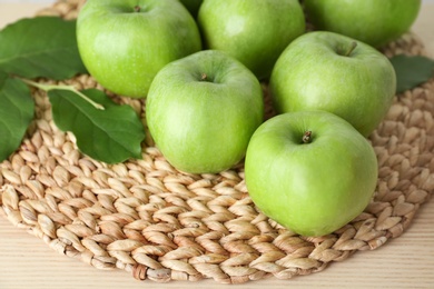 Fresh green apples on wicker mat