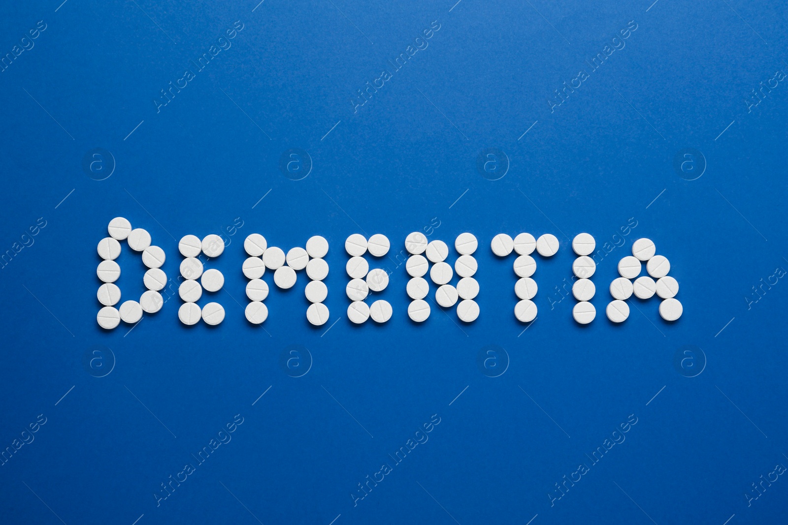 Photo of Word Dementia made of pills on blue background, flat lay