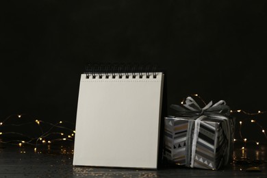 Photo of Notepad with space for text and gift on wooden table