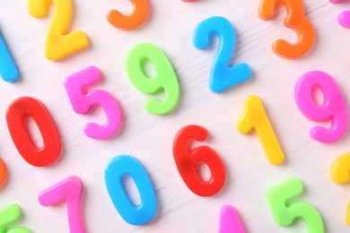 Colorful numbers on white wooden school desk, flat lay