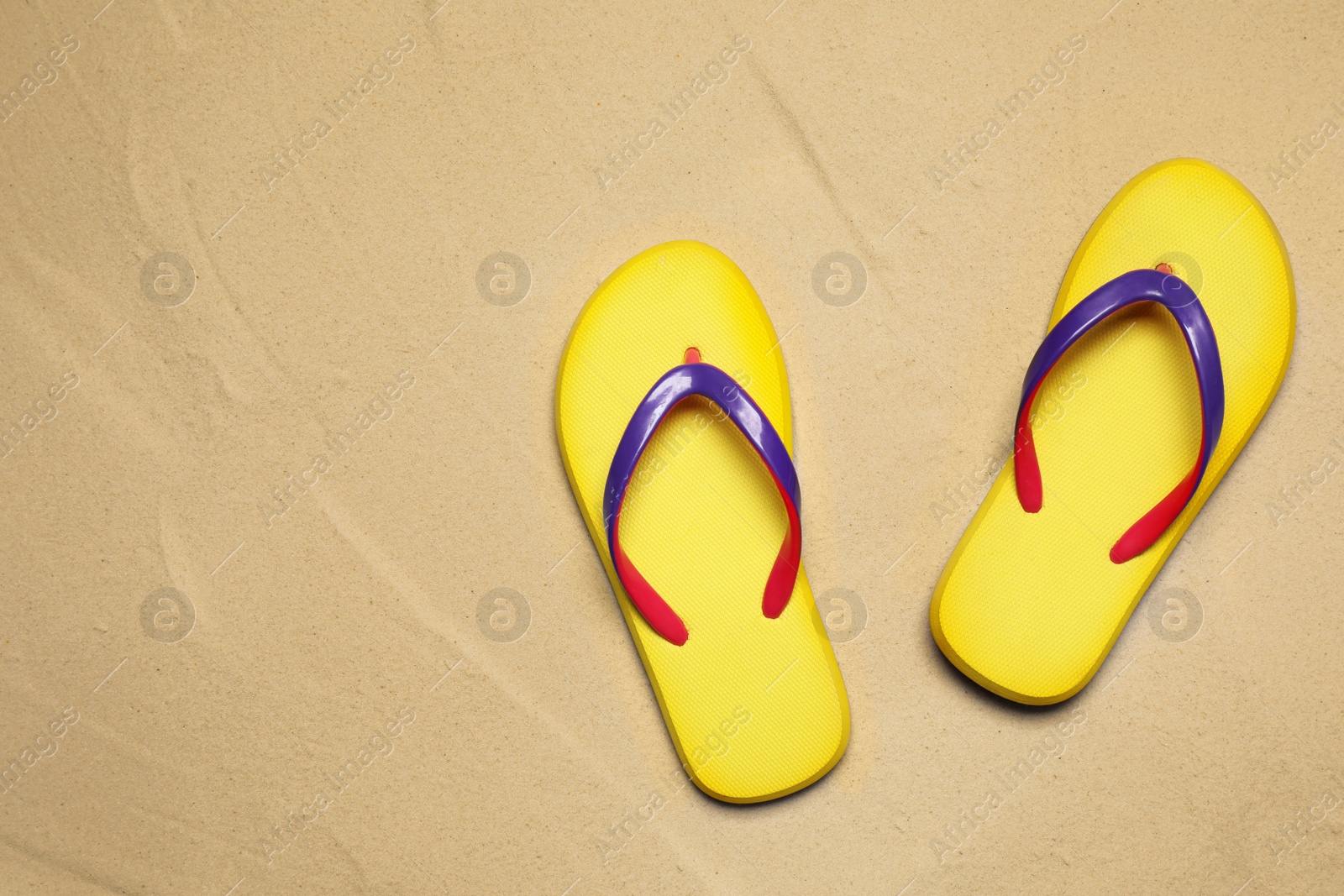 Photo of Yellow flip flops on sand, flat lay with space for text. Beach accessory