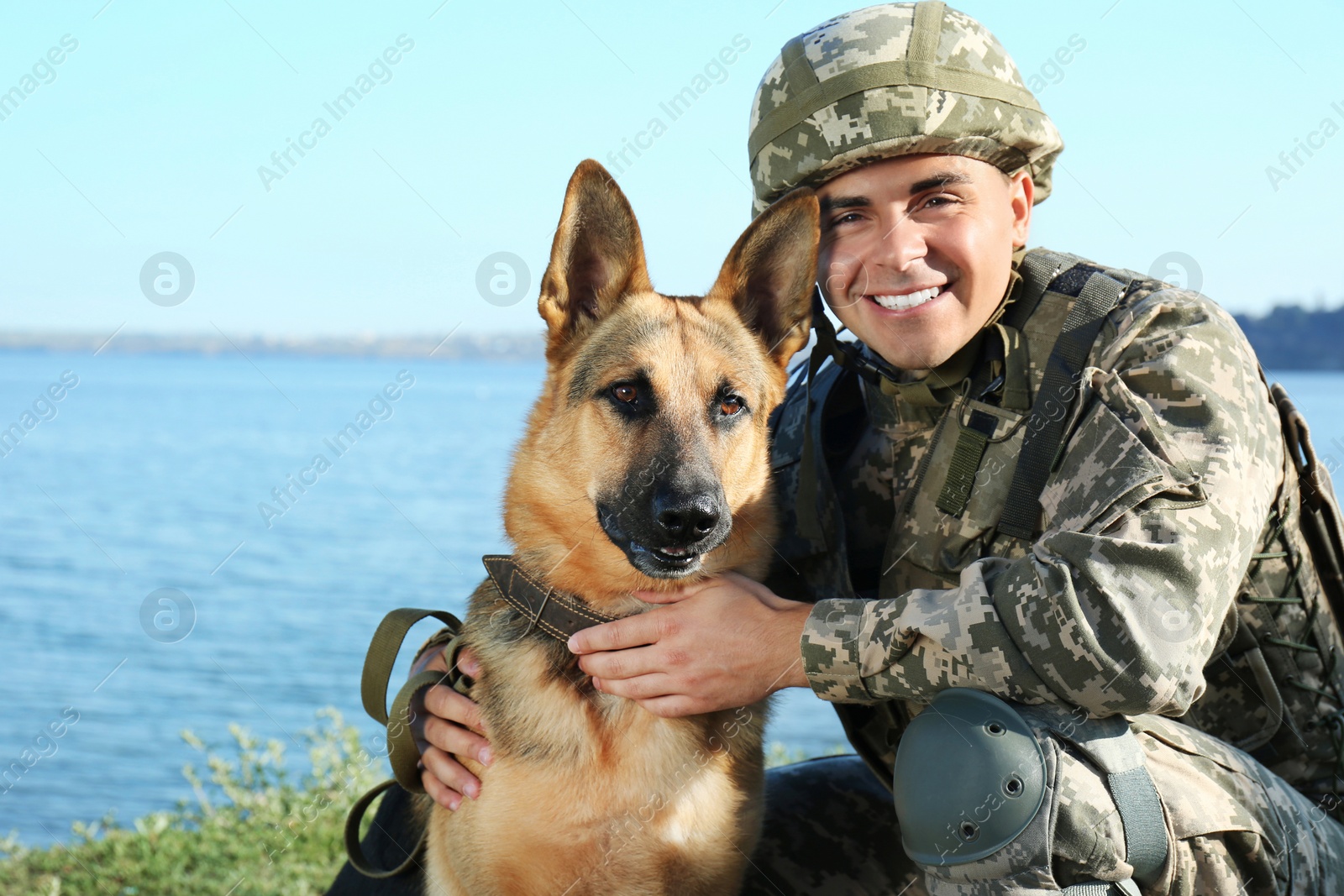 Photo of Man in military uniform with German shepherd dog near river