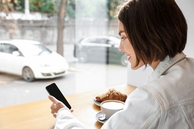 Special Promotion. Happy young woman using smartphone at table in cafe