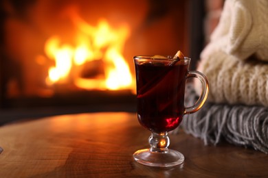 Photo of Tasty mulled wine, knitwear and blurred fireplace on background