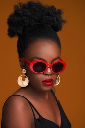 Photo of Fashionable portrait of beautiful woman with stylish sunglasses on light brown background