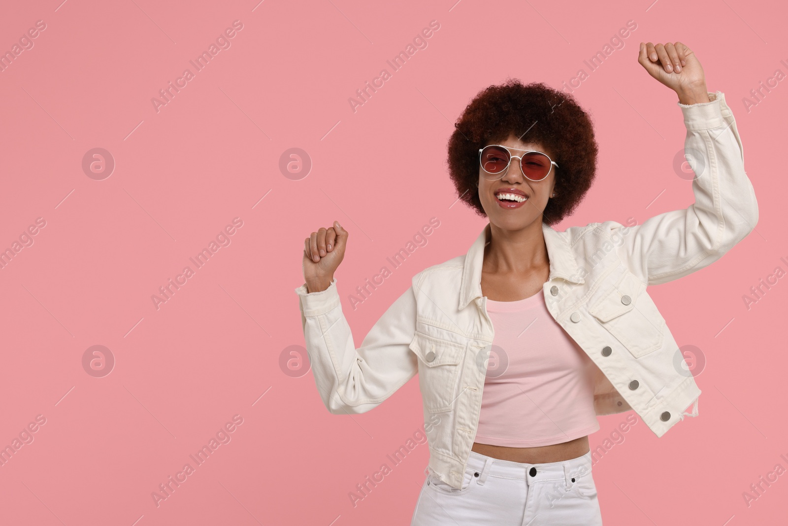 Photo of Happy young woman dancing on pink background. Space for text