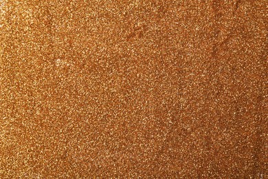 Photo of Beautiful shiny bronze glitter as background, closeup