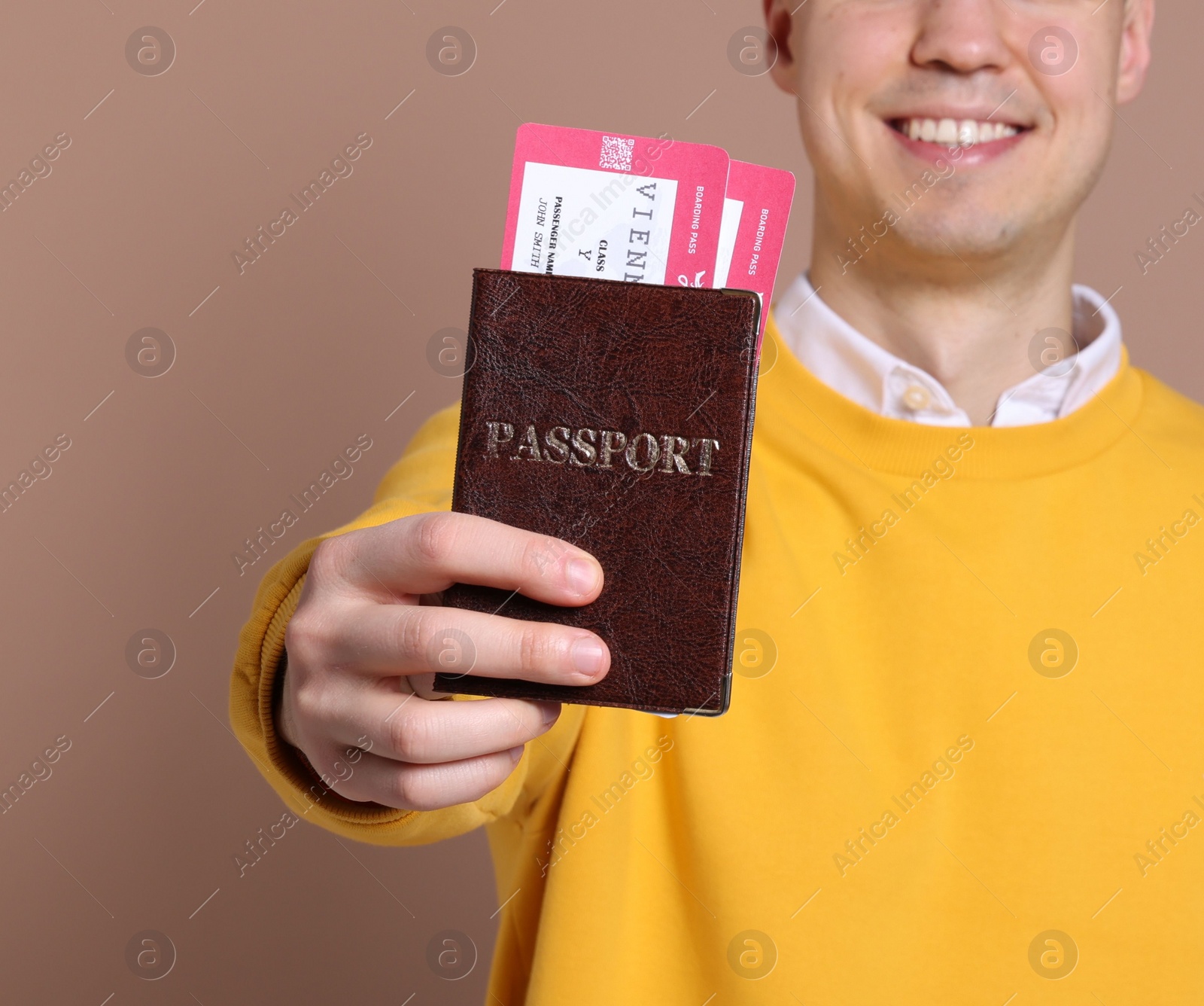 Photo of Smiling man showing passport and tickets on beige background, closeup