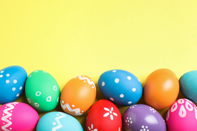 Photo of Colorful Easter eggs on yellow background, flat lay. Space for text