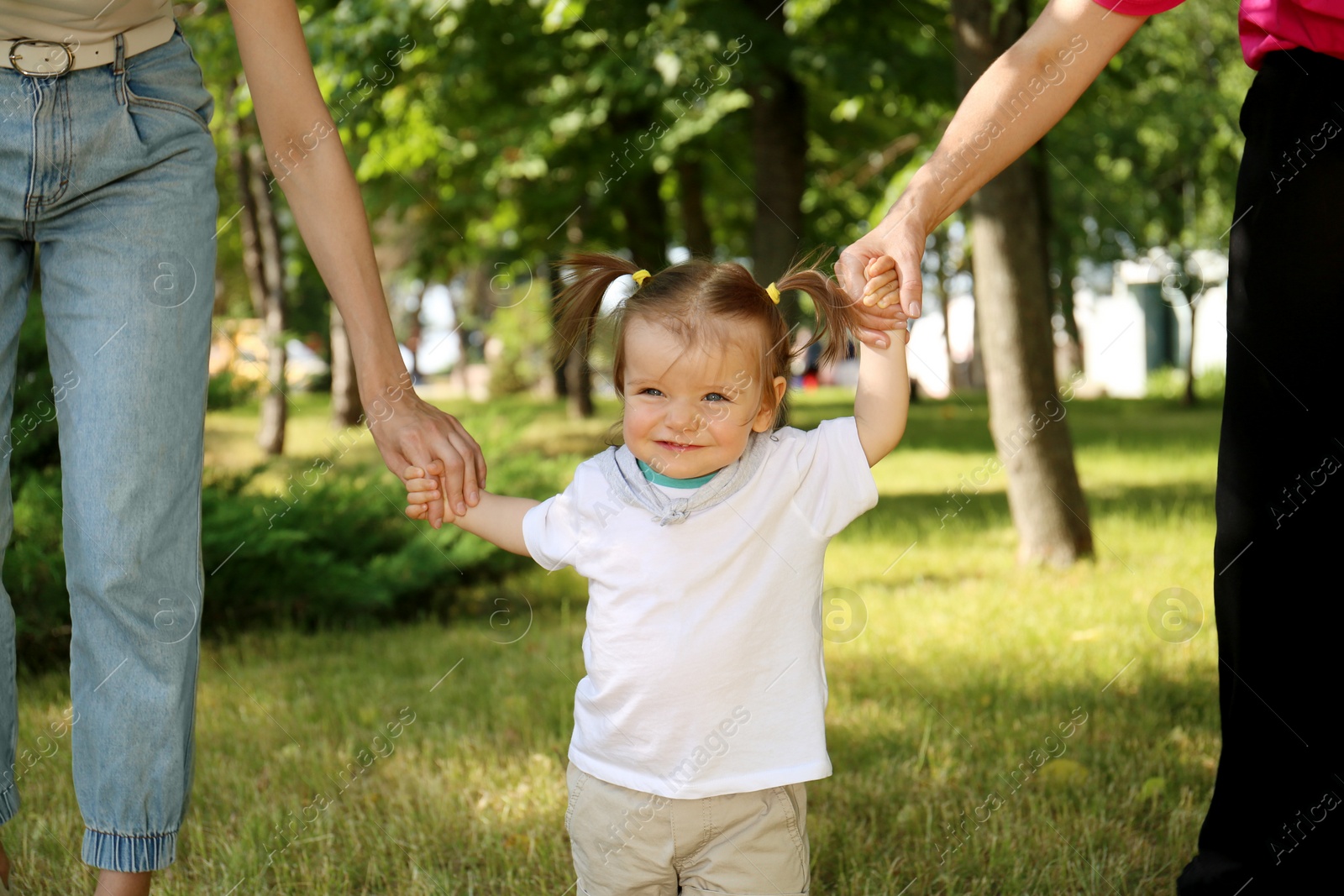 Photo of Women supporting baby girl while she learning to walk in park