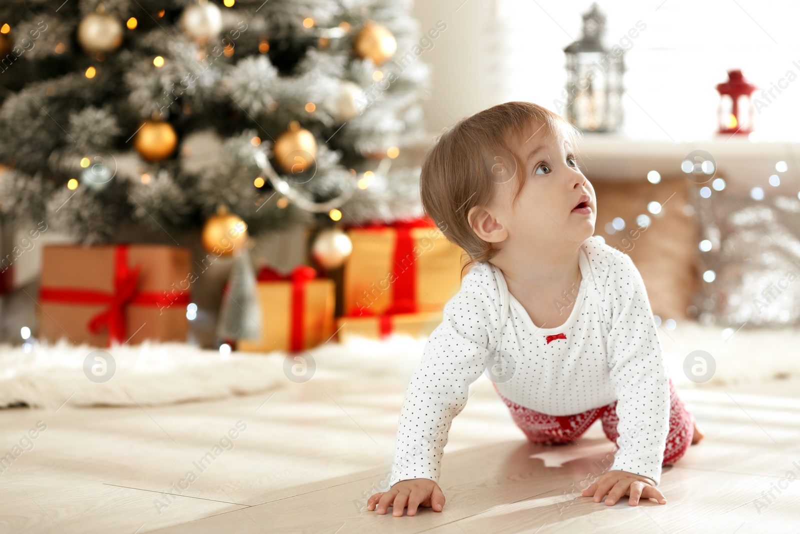 Photo of Cute baby on floor near Christmas tree