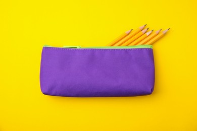 Photo of Many sharp pencils in pencil case on yellow background, top view