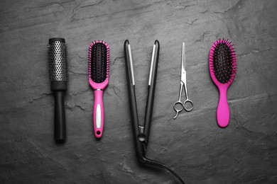 Photo of Flat lay composition of professional hairdresser tools on dark grey table