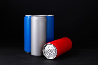 Photo of Energy drinks in colorful cans on black wooden table