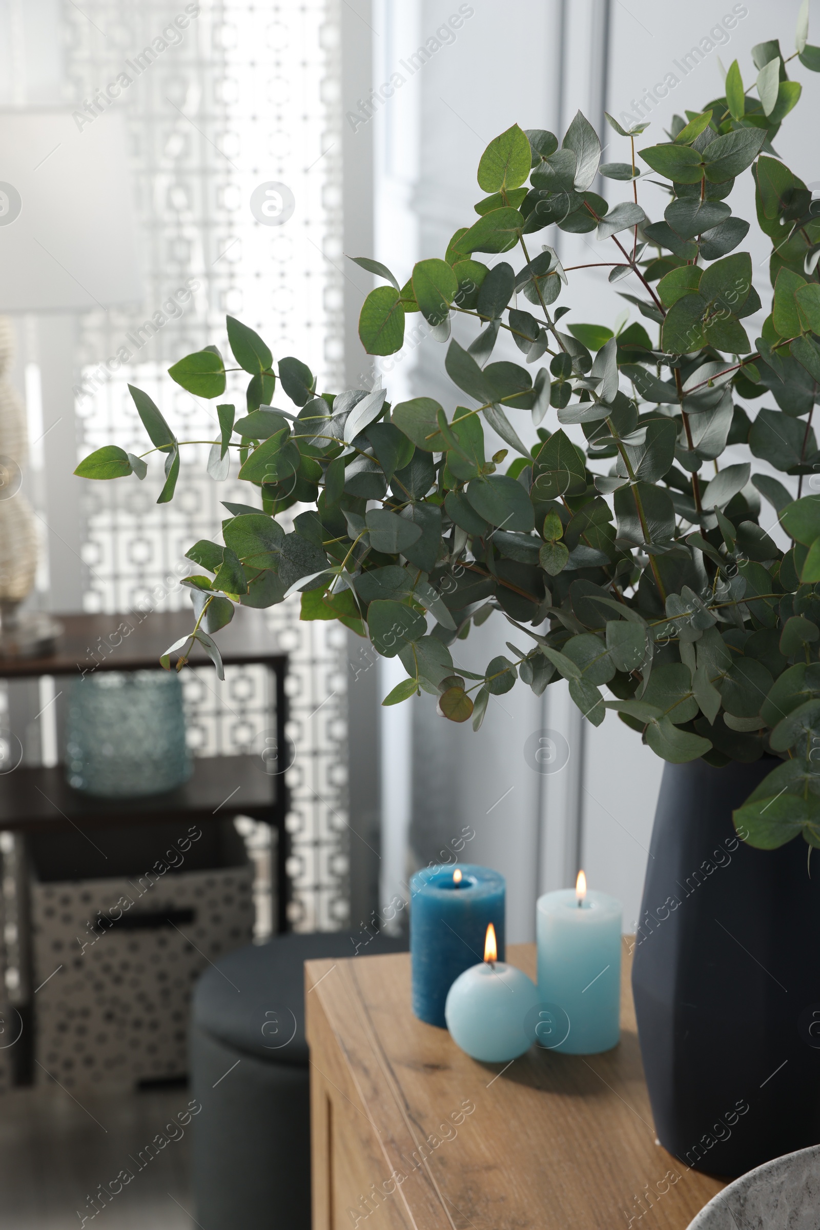 Photo of Eucalyptus branches and burning candles on bathroom vanity. Interior design