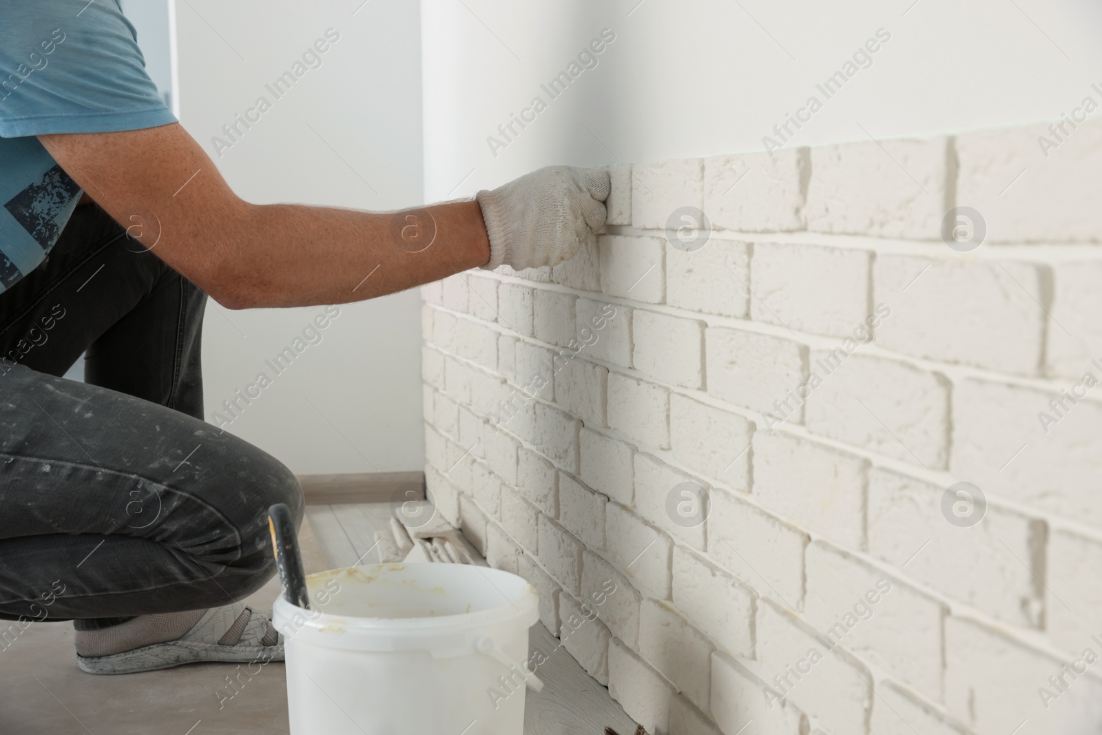 Photo of Worker installing decorative wall tiles in room, closeup