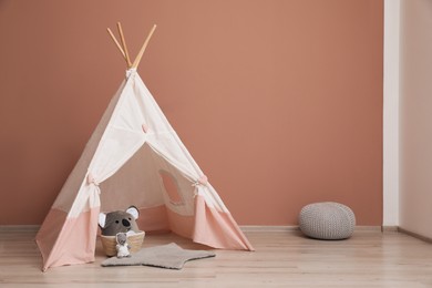 Photo of Cute child room interior with play tent near pink wall