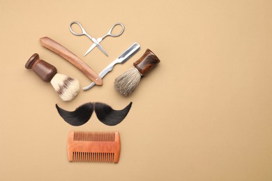 Artificial moustache and barber tools on beige background, flat lay. Space for text