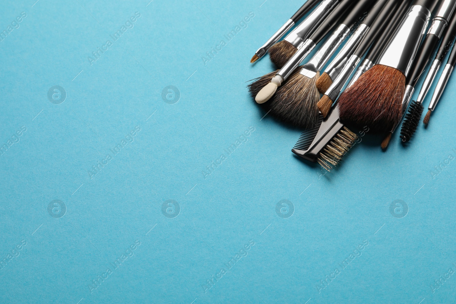 Photo of Set of makeup brushes on light blue background, space for text