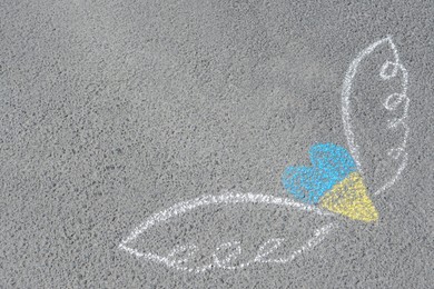 Heart and wings drawn with blue and yellow chalks on asphalt outdoors. Space for text