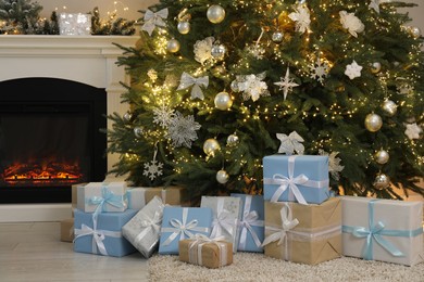 Many gift boxes under beautiful Christmas tree near fireplace at home