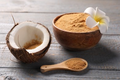 Photo of Coconut sugar, bowl, spoon, flower and fruit on grey wooden table, closeup