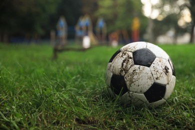 Dirty leather soccer ball on grass outdoors, space for text