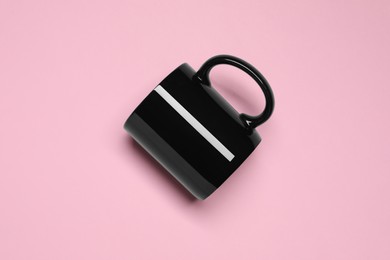 Photo of Black ceramic mug on pink background, top view