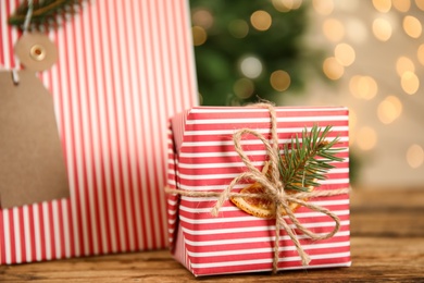 Photo of Striped Christmas gift box and bag on wooden table, closeup