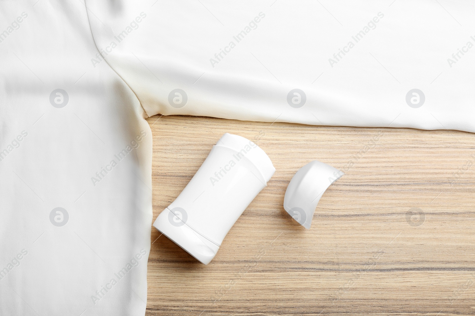 Photo of Clothes with stain and deodorant on wooden background, top view