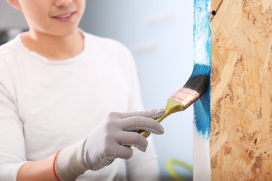 Photo of Male decorator painting wall with brush indoors