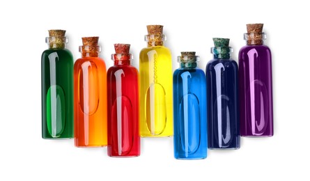 Glass bottles with different food coloring on white background, top view