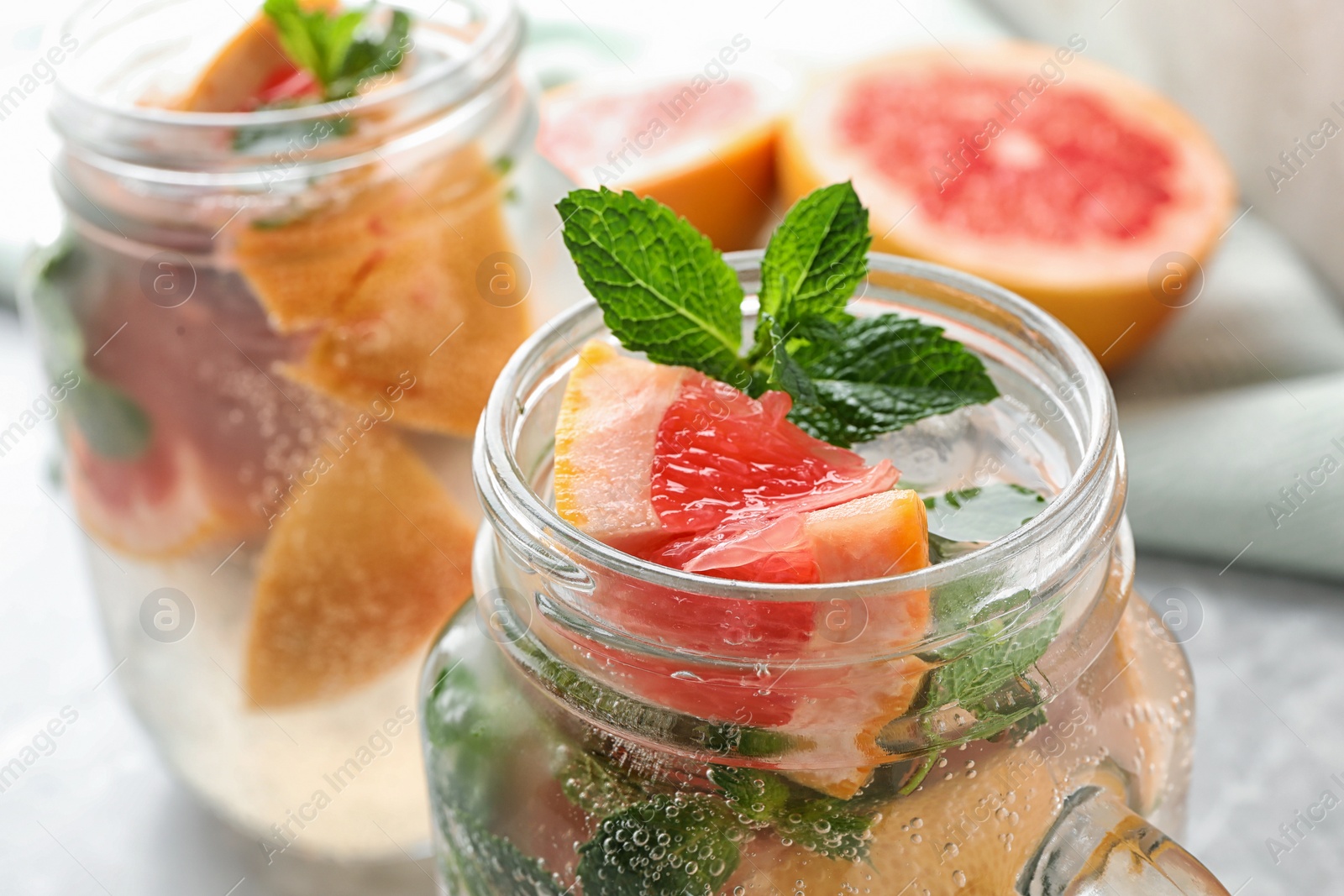 Photo of Mason jar of refreshing drink with grapefruit and mint on table, closeup view. Space for text