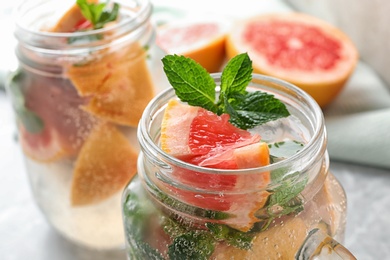 Photo of Mason jar of refreshing drink with grapefruit and mint on table, closeup view. Space for text