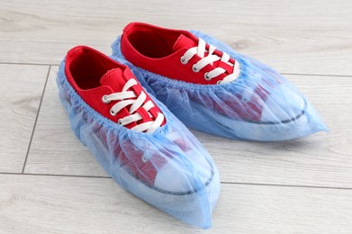 Sneakers in blue shoe covers on light wooden floor