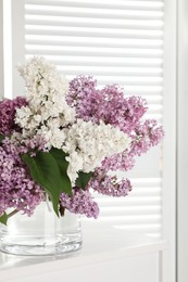 Beautiful lilac flowers in glass vase on white table