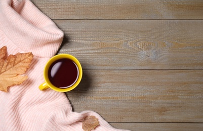 Photo of Pink sweater, cup of tea and autumn leaves on wooden background, flat lay. Space for text