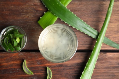 Photo of Fresh aloe drink in glass and leaves on wooden table, flat lay