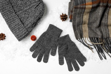 Stylish grey woolen gloves, scarf and hat on white background, top view